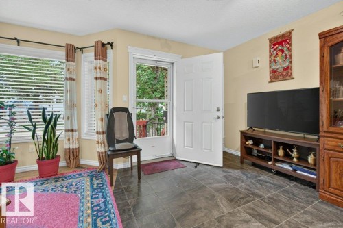 Entryway featuring dark gray tile flooring, a white paneled entry door, and a screen door - 11330 101 Street, Edmonton, AB 