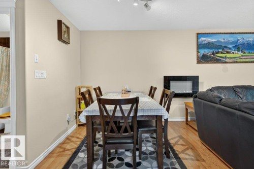 Open-concept dining area featuring wood-finish flooring, recessed lighting, and a modern wall-mounted fireplace - 11330 101 Street, Edmonton, AB 