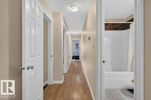 Hallway with wood-finish flooring, neutral wall paint, and white trim - 11330 101 Street, Edmonton, AB 