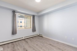 Spacious room featuring wood-finish flooring, a large window with privacy drapes, and light blue walls - 
