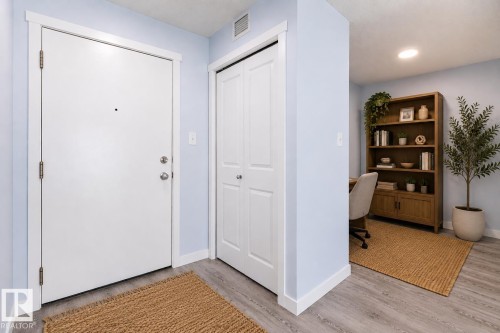 Entryway featuring a white door with brushed nickel hardware, light blue wall paint, white trim, and wood-finish flooring - 403 25 Element Dr, St. Albert, AB - Indoor Photo Showing Other Room