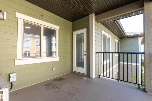 Spacious concrete patio with durable vinyl siding, a clear glass door, multiple windows, and a black metal railing - 403 25 Element Dr, St. Albert, AB - Outdoor With Deck Patio Veranda With Exterior