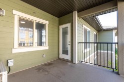 Spacious concrete patio with durable vinyl siding, a clear glass door, multiple windows, and a black metal railing - 