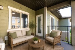 Covered balcony featuring horizontal siding, a glass-paneled door, and a black metal railing - 
