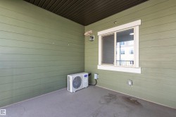 Private covered patio featuring a large window, a wall-mounted exterior light fixture, and horizontal siding - 