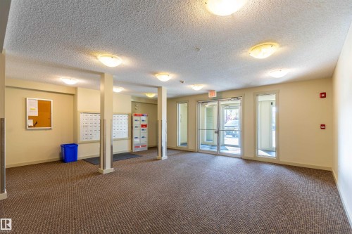 Spacious common area featuring textured carpet flooring, recessed ceiling lighting, and beige painted walls - 403 25 Element Dr, St. Albert, AB - Indoor Photo Showing Other Room