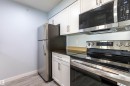Modern kitchen featuring white shaker cabinetry, dark countertops, and stainless steel appliances including a refrigerator, range, and microwave - 403 25 Element Dr, St. Albert, AB  - Indoor Photo Showing Kitchen 