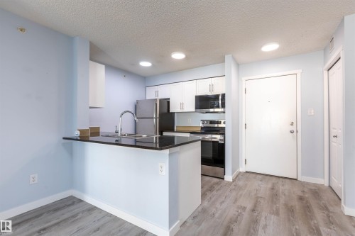 Kitchen featuring white cabinetry, stainless steel appliances, dark countertop, and an integrated breakfast bar - 403 25 Element Dr, St. Albert, AB - Indoor Photo Showing Kitchen