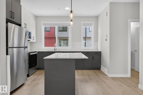 Contemporary kitchen featuring a central island with a light-toned countertop - 33 11910 35 Avenue, Edmonton, AB 