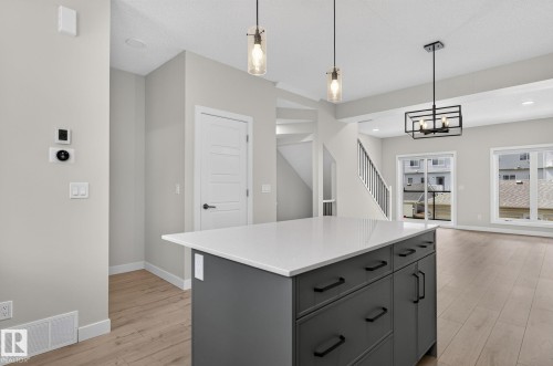 Kitchen island featuring a white countertop and dark gray cabinetry with black hardware - 33 11910 35 Avenue, Edmonton, AB 