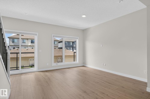 Spacious interior room featuring light wood-finish flooring, recessed lighting, and a white trim package - 33 11910 35 Avenue, Edmonton, AB 