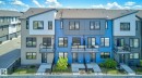 Blue horizontal siding exterior with black window frames, a gray front door featuring a vertical glass insert, and a concrete walkway - 33 11910 35 Avenue, Edmonton, AB 