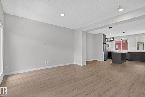 Open-concept living space featuring wood-finish flooring, recessed lighting, and a modern kitchen - 33 11910 35 Avenue, Edmonton, AB 