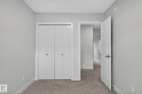 Room featuring a single window with white trim, light gray painted walls, and textured gray carpeting - 33 11910 35 Avenue, Edmonton, AB 