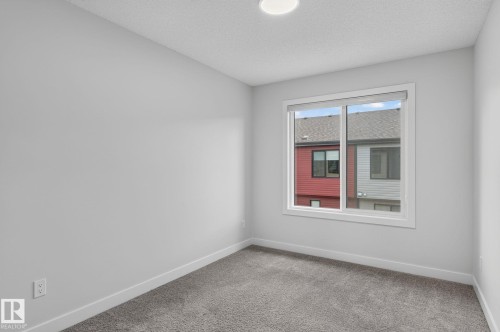 Neutral-toned room featuring a soft gray carpet, white baseboards, and light gray painted walls - 33 11910 35 Avenue, Edmonton, AB 