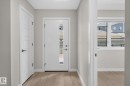 Entryway featuring wood-finish flooring, a modern white door with frosted glass paneling, and a contemporary panel-style interior door - 33 11910 35 Avenue, Edmonton, AB 