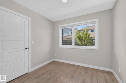 Neutral toned room featuring wood-finish flooring, light gray wall paint, and a multi-pane window - 33 11910 35 Avenue, Edmonton, AB 