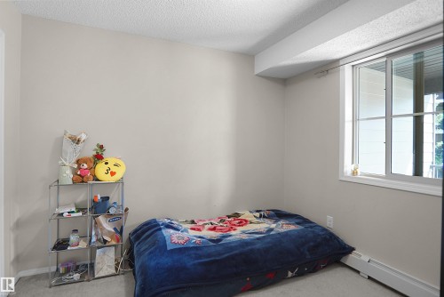 Neutral-toned room featuring a window with white framing, light-colored walls, and textured ceiling - 215 1070 Mcconachie Blvd, Edmonton, AB 