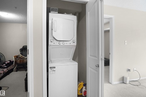 Dedicated laundry area featuring a white stacked washer and dryer unit - 215 1070 Mcconachie Blvd, Edmonton, AB 