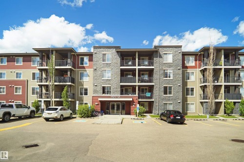 Contemporary multi-story building featuring a stone facade and red and beige siding - 215 1070 Mcconachie Blvd, Edmonton, AB 
