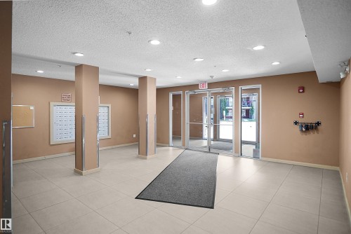 Building entry with light-toned tiled flooring, recessed ceiling lighting, and multiple mailboxes - 215 1070 Mcconachie Blvd, Edmonton, AB 