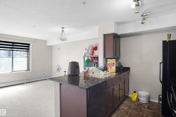 Kitchen featuring dark cabinetry, dark countertops, and a built-in dishwasher - 