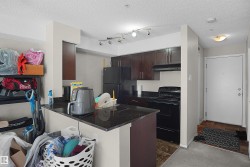 Kitchen featuring wood-finish cabinetry, black appliances, and dark granite countertops - 