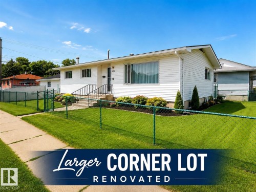 White siding exterior featuring a prominent front entrance with black handrails, a large front window, and a chain-link fence enclosing the front yard - 4304 121 Avenue, Edmonton, AB 