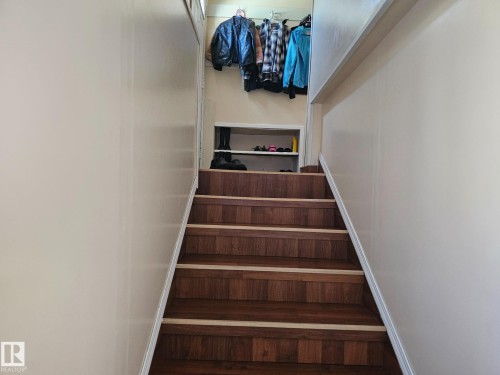 Stairwell with wood-finish treads featuring light-toned risers and an integrated storage niche - 4304 121 Avenue Nw, Edmonton, AB - Indoor Photo Showing Other Room