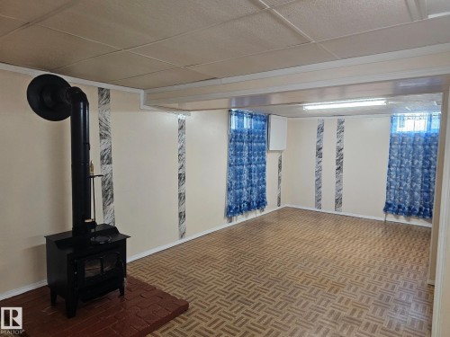 Expansive room featuring a black wood-burning stove on a red brick hearth - 4304 121 Avenue Nw, Edmonton, AB - Indoor Photo Showing Other Room