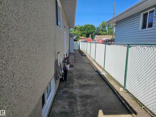 Exterior featuring textured stucco siding, white window trim, and a concrete walkway - 4304 121 Avenue Nw, Edmonton, AB - Outdoor With Exterior