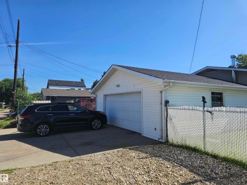 Detached garage featuring white vinyl siding, a white garage door, and a dark shingle roof - 4304 121 Avenue Nw, Edmonton, AB - Outdoor