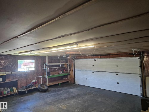 Garage interior with a concrete floor, exposed ceiling joists, and fluorescent lighting fixtures - 4304 121 Avenue Nw, Edmonton, AB - Indoor Photo Showing Garage