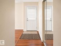 Entryway featuring a white paneled door with horizontal blinds, wood-finish flooring, and a mirrored closet door - 4304 121 Avenue Nw, Edmonton, AB  - Indoor Photo Showing Other Room 