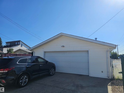 Detached garage featuring white vinyl siding and a white panel garage door - 4304 121 Avenue Nw, Edmonton, AB - Outdoor With Exterior