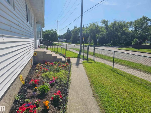 White siding exterior with a concrete pathway and black wrought iron railing - 4304 121 Avenue Nw, Edmonton, AB - Outdoor