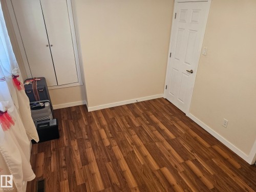 Wood-finish flooring throughout, paired with neutral-toned walls and white trim - 4304 121 Avenue Nw, Edmonton, AB - Indoor Photo Showing Other Room