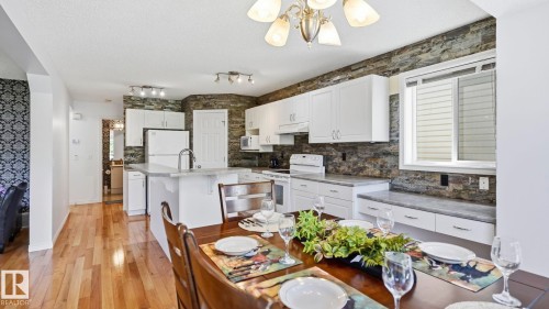 Open-concept dining and kitchen area featuring wood-finish flooring - 3591 Mclean Crescent, Edmonton, AB 