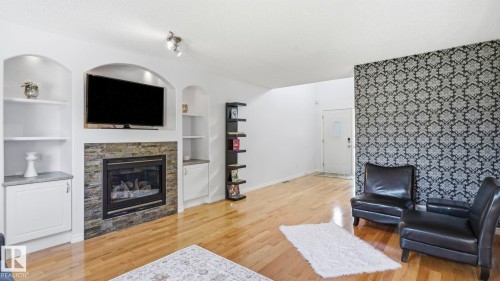 Living area featuring wood-finish flooring and a decorative accent wall - 3591 Mclean Crescent, Edmonton, AB 