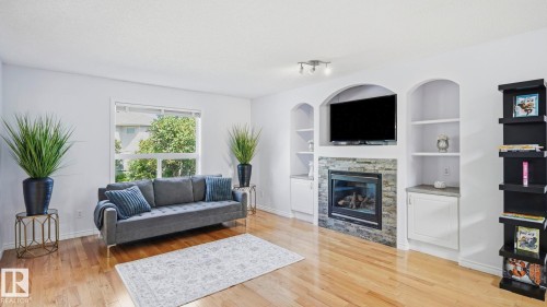 Light wood-finish flooring complements the white walls of this living area - 3591 Mclean Crescent, Edmonton, AB 