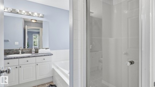 Bathroom featuring a white vanity with a dark countertop, an undermount sink, and a mirrored medicine cabinet - 3591 Mclean Crescent, Edmonton, AB 