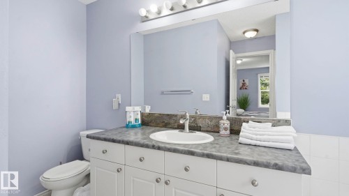 Bathroom featuring a white vanity with a dark countertop, an undermount sink, and a large wall-mounted mirror - 3591 Mclean Crescent, Edmonton, AB 
