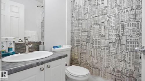 Bathroom featuring a white vanity with a dark countertop, an undermount sink, and a brushed nickel faucet - 3591 Mclean Crescent, Edmonton, AB 