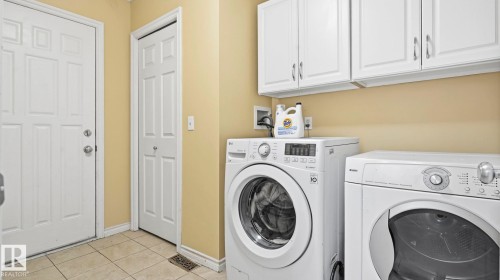 Dedicated laundry space featuring white upper cabinetry, light-toned wall paint, and tiled flooring - 3591 Mclean Crescent, Edmonton, AB 