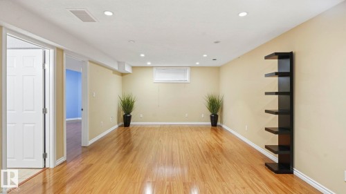 Spacious room featuring wood-finish flooring, recessed lighting, a white trim package, and a built-in shelving unit - 3591 Mclean Crescent, Edmonton, AB 
