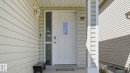 Front entry featuring a white paneled door with decorative glass insert, sidelight, and an overhead porch light - 3591 Mclean Crescent, Edmonton, AB 