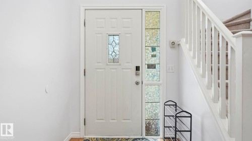 Entryway featuring a white paneled door with decorative glass insert, sidelight, and smart lock - 3591 Mclean Crescent, Edmonton, AB 