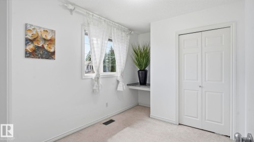 Recessed window with white trim, built-in shelving with a stone-finish countertop, white bi-fold closet doors, and light-toned carpeting - 3591 Mclean Crescent, Edmonton, AB 