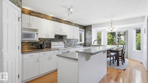 Modern kitchen with white cabinetry and stone backsplash - 3591 Mclean Crescent, Edmonton, AB 