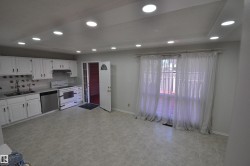 Open-concept space featuring a kitchen with white cabinetry, stainless steel dishwasher, and a white range - 